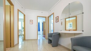 A hallway with a grey sofa, a mirror, and framed pictures on the wall. - PRIMADOM Aparthotel (Geneva)