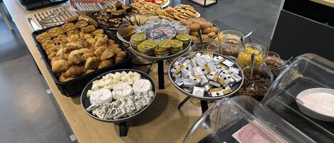Un bufé con diferentes opciones de comida, incluyendo pasteles, quesos, frutas y salsas.
