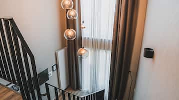 Una escalera moderna con barandilla negra, un tapete azul al final y una lámpara colgante.