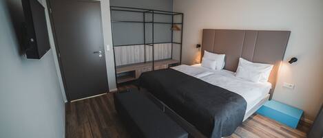 A modern bedroom with a bed, bench, and built-in shelving unit.