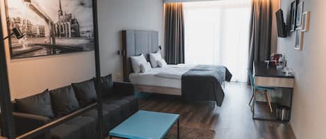 Une chambre d’hôtel moderne équipée d’un lit, d’un canapé, d’un bureau et d’une machine à café.
