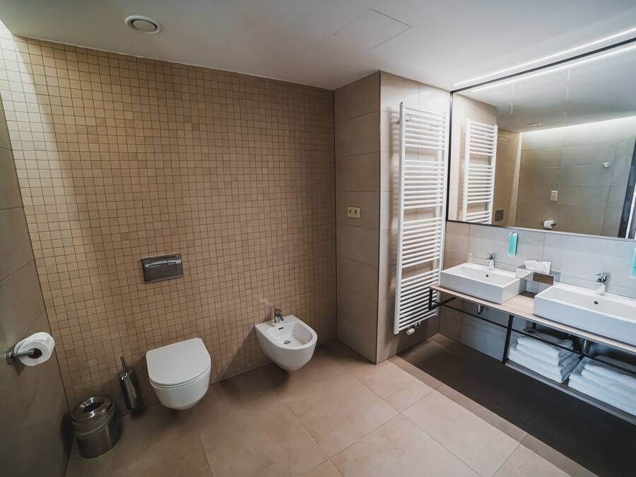 A modern bathroom with a toilet, bidet, and dual sinks.
