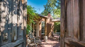 A rustic outdoor patio with wooden furniture and a stone fireplace. - Authentic Santa Fe Home-Step into History & Charm (Santa Fe)