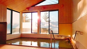 Un jacuzzi con vista a árboles a través de amplios ventanales.