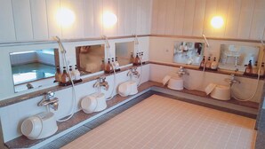 Un baño con varios lavamanos, espejos y dispensadores de jabón.