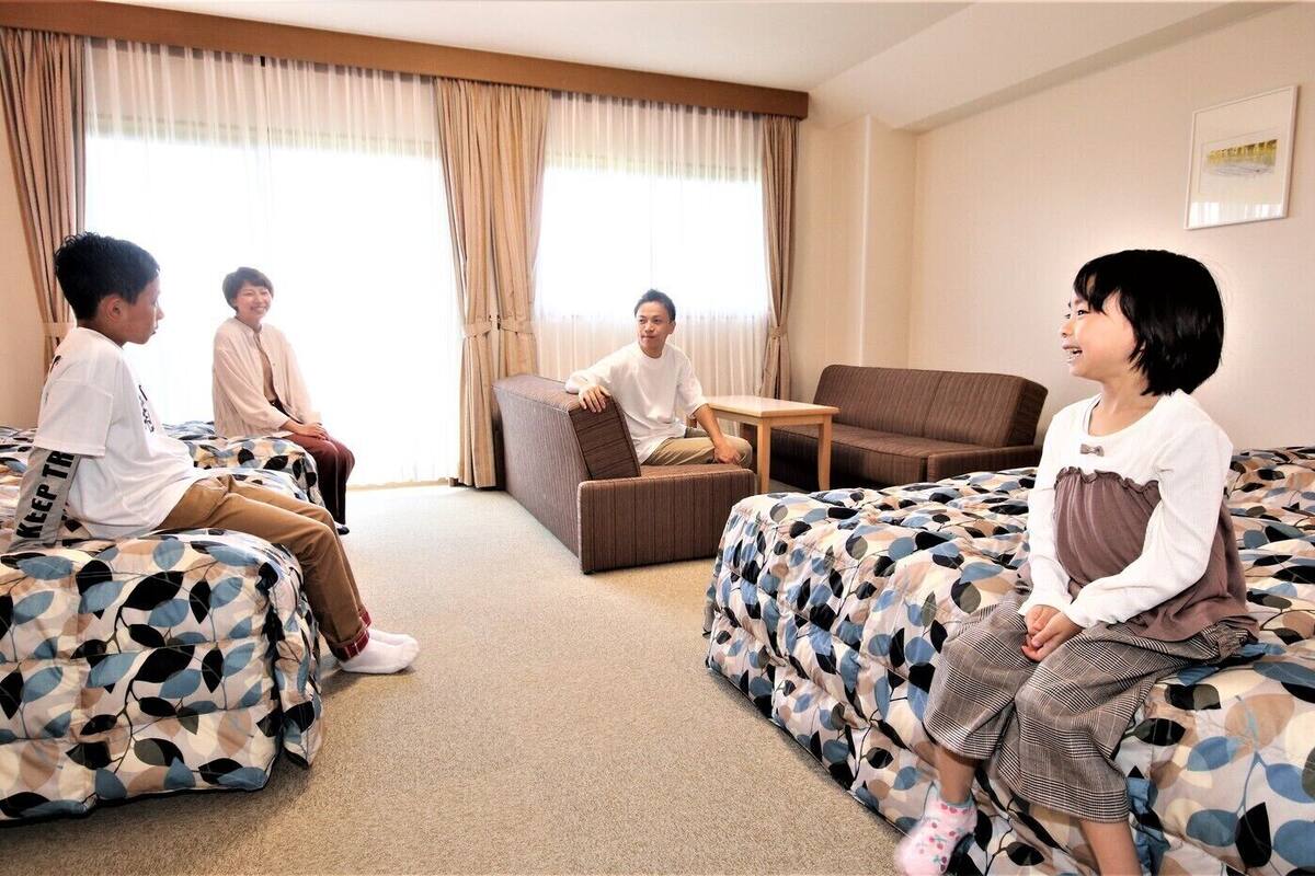 A hotel room with two beds, a sofa, and a small table.
