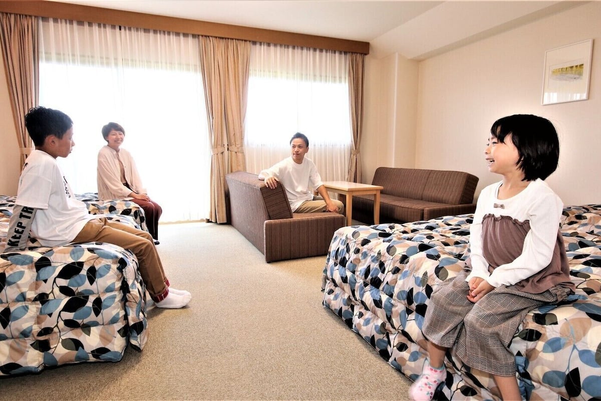 Una habitación de hotel con dos camas, un sofá y una pequeña mesa.