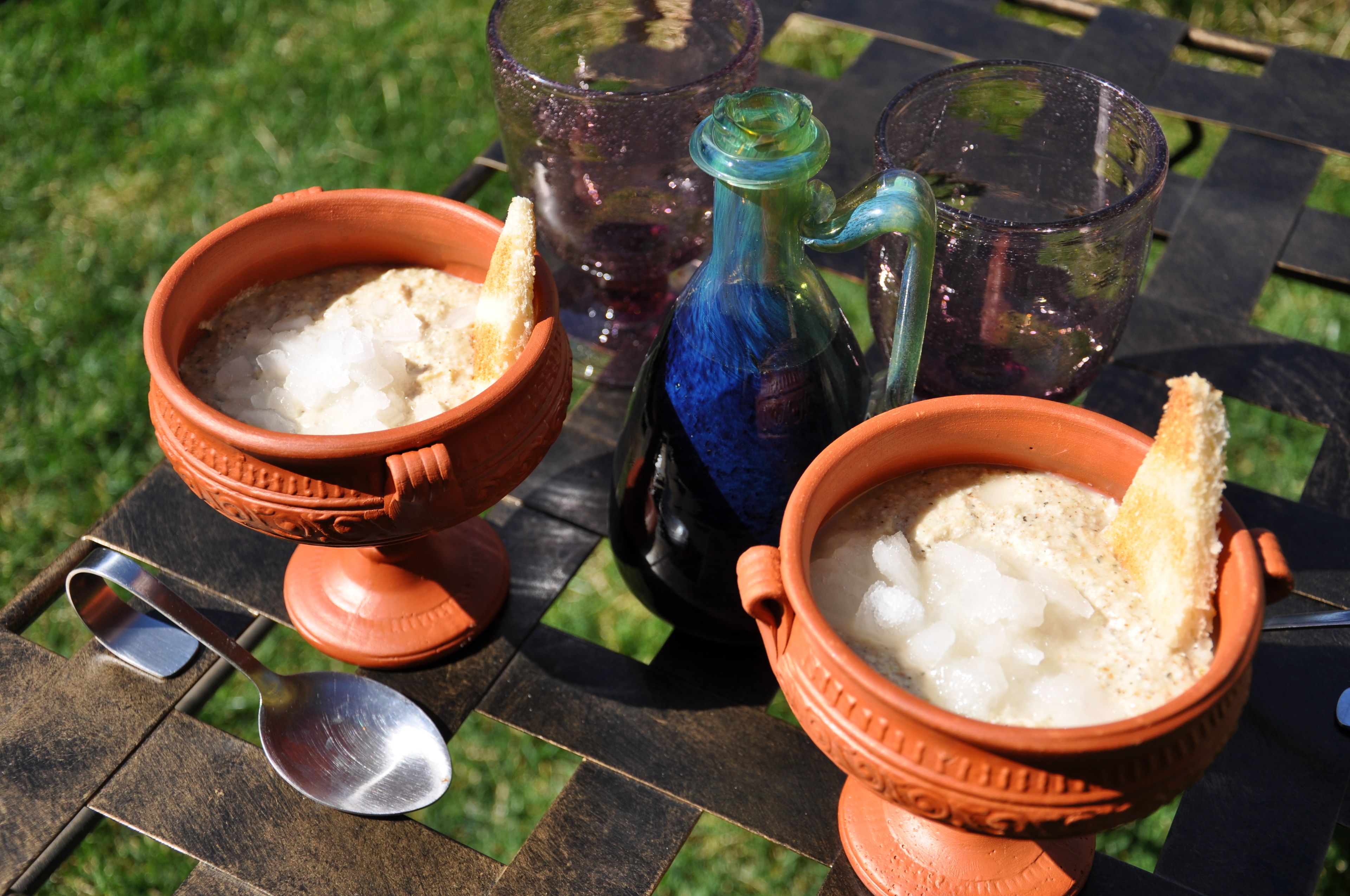 Zwei Terrakotta-Schalen mit einer weißen Substanz und Brot auf einem Tisch.