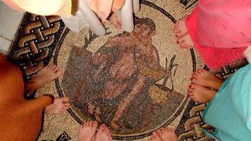 A mosaic floor with a central figure surrounded by people standing around it.