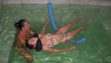 Una persona recostada en una piscina con un flotador azul.