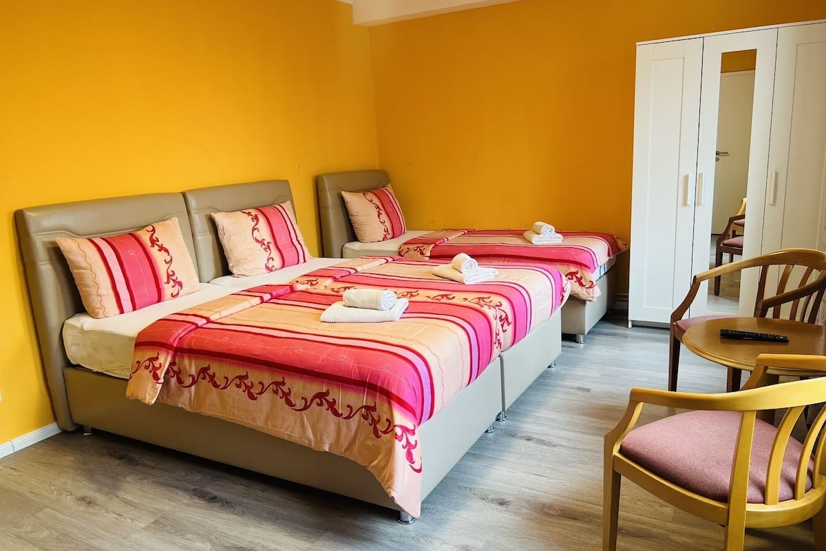 Een hotelkamer met twee bedden, een houten stoel en een garderobe.