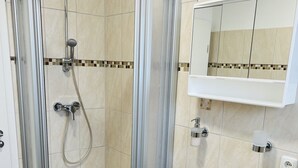 Un bagno moderno con doccia vetrata, lavandino bianco e specchio sopra il lavandino.