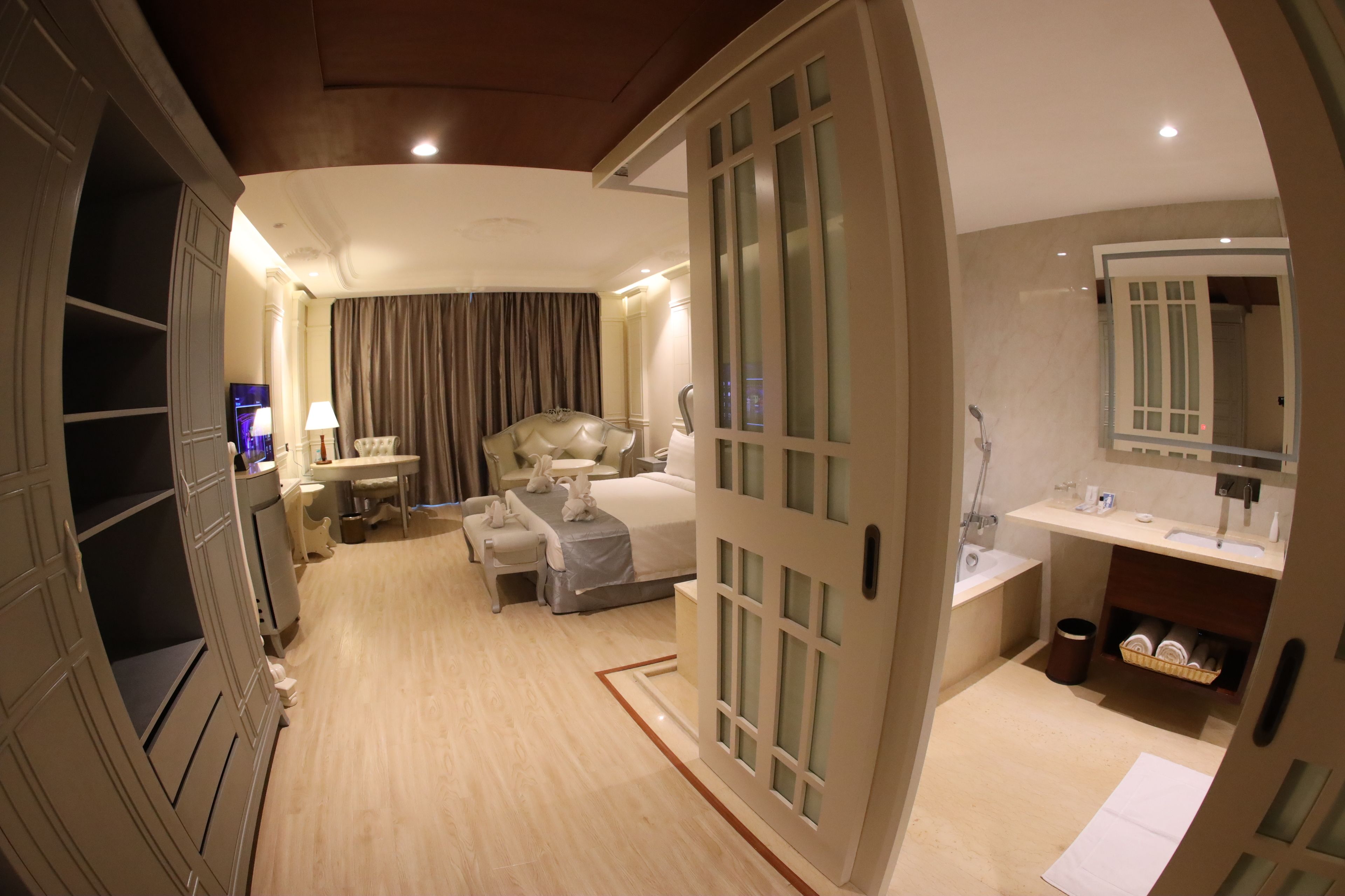 A hotel room with a bed, bedside table, lamp, and a bathroom with a sink and mirror.