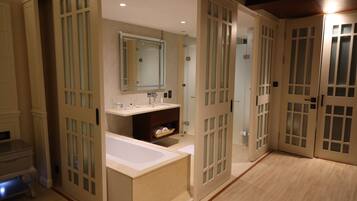 A modern bathroom with a freestanding bathtub, a vanity with a mirror, and frosted glass doors.