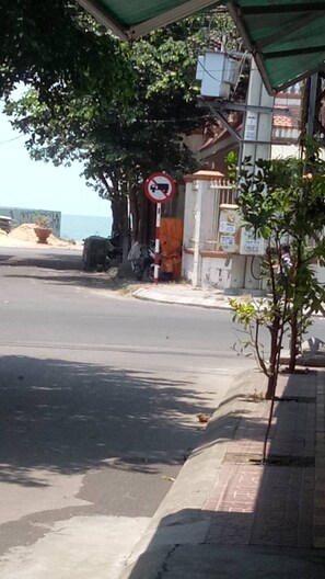 Eine Straße mit einem Verbotsschild zum Parken, einem Gebäude mit einer grünen Markise und einem Baum.