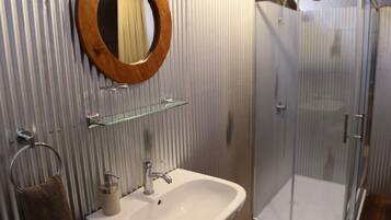 Un baño con lavamanos blanco, espejo de madera y cabina de ducha de cristal.