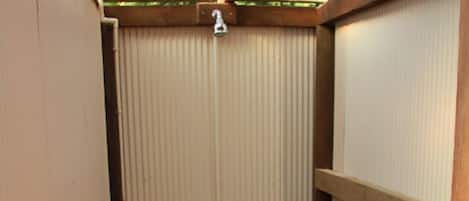 A narrow corridor with a wooden bench and a closed metal gate.