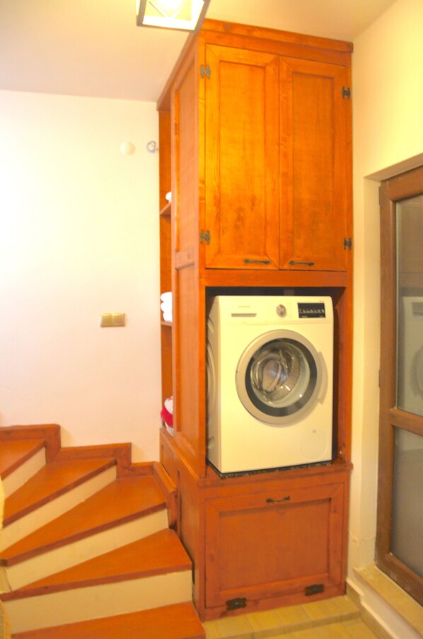 A laundry room with a washing machine and wooden cabinets.