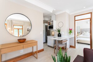 A modern living room with a wooden console table, a round mirror, a white desk, and a comfortable seating area.
