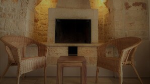 A stone fireplace with two wicker chairs and a small table in front. - Masseria Grofoleo (Locorotondo)