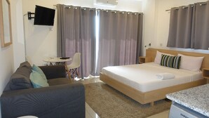 Una habitación de hotel con cama, escritorio, silla y televisor montado en la pared.