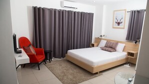 Un dormitorio moderno con una cama, una silla roja, un escritorio y una mesa de vidrio.