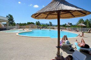 Una piscina al aire libre de temporada, sombrillas