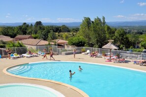 Una piscina al aire libre de temporada, sombrillas