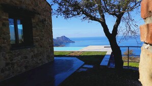Un edificio de piedra con vista al mar y un árbol en primer plano.