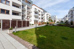 A modern apartment complex with multiple balconies, a well-maintained lawn, and a gated entrance.