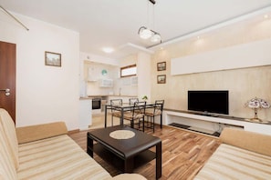 Ein modernes Wohnzimmer mit einer Couch, einem Couchtisch, einem Fernseher und einem Essbereich mit Stühlen und einem Tisch.