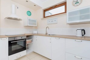 Una cocina moderna con armarios blancos, horno empotrado, lavabo y ventana sobre la encimera.