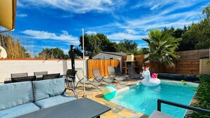 A backyard with a swimming pool, lounge chairs, a sofa, and a wooden deck. - Loft Nature Bien-être Piscine Chauffée Privée Tarn (Peyrole)