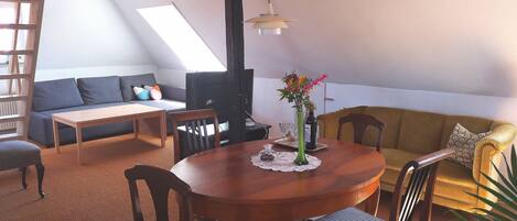 A cozy living room with a wooden dining table, chairs, a sofa, and a TV.