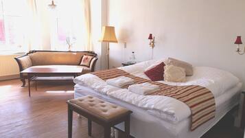 Une chambre bien éclairée, avec un grand lit, une table de chevet, une chaise et une lampe.