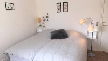 Un dormitorio con cama, mesita de noche, lámpara y decoración en la pared.