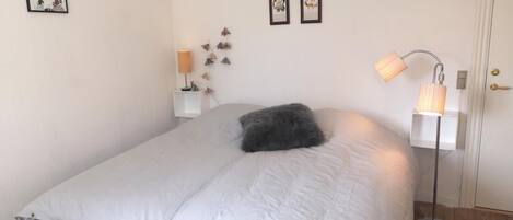 Ein Schlafzimmer mit Bett, Nachttisch, Lampe und Wandbildern.