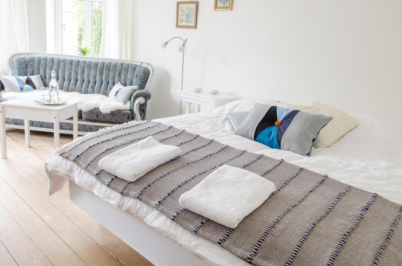 Un dormitorio con cama, sofá, mesita y mesita de noche.