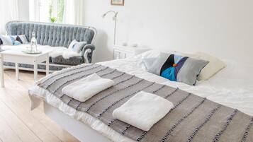 Un dormitorio con cama, sofá, mesita y mesita de noche.