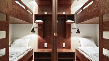 Una habitación con literas, estanterías de madera y lámparas de noche.