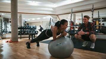 Un gimnasio con suelos de madera, pelotas de ejercicio y equipamiento de levantamiento de pesas.