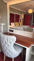 Un dormitorio con una cama, un escritorio y una silla. Hay un espejo en la pared.