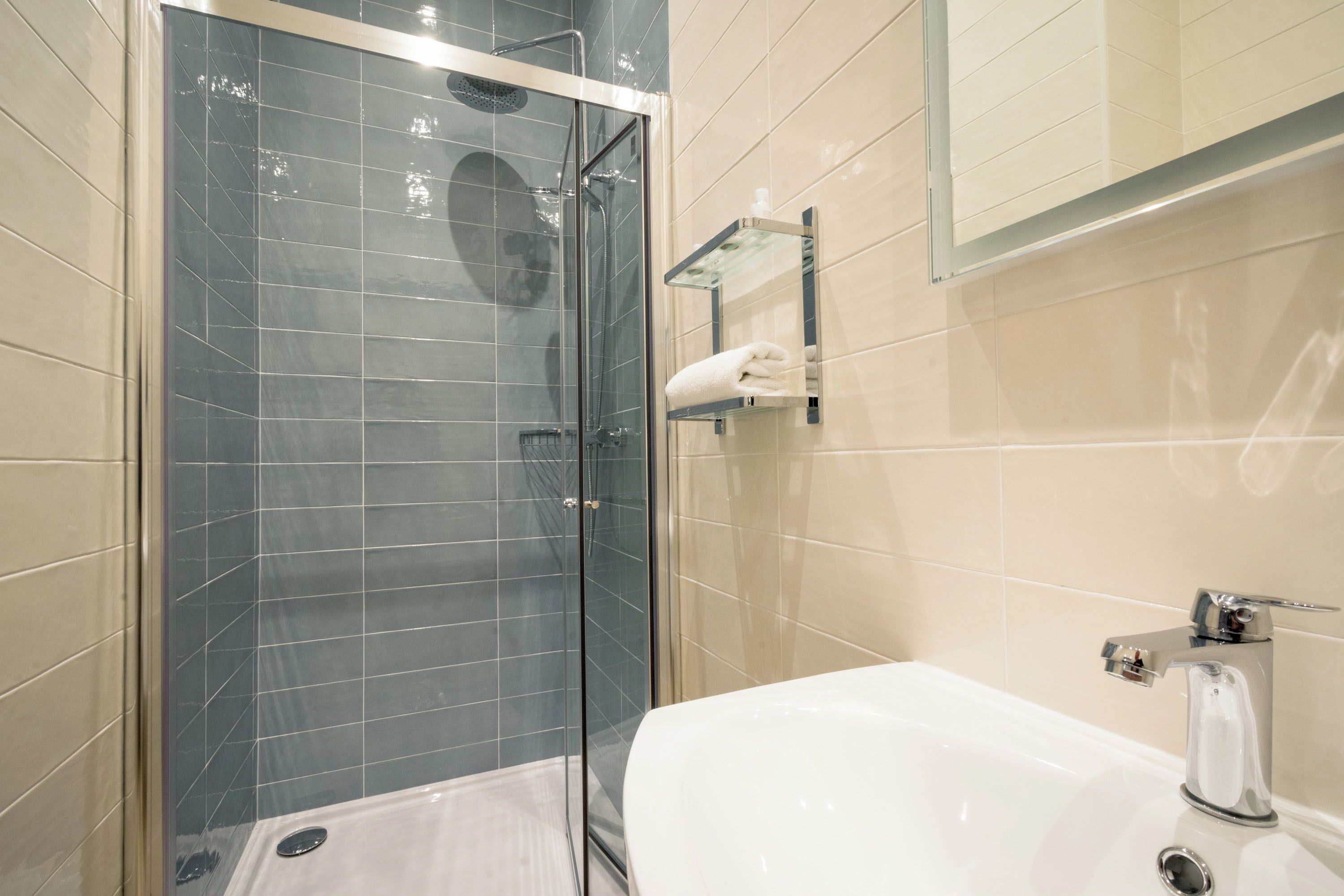 A modern bathroom with a glass-enclosed shower, a white bathtub, and a towel rack.