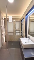Un baño moderno con cabina de ducha de vidrio, un lavabo blanco y un espejo.