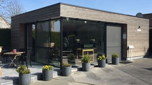 A modern building with a glass facade, outdoor seating, and potted plants. - B&B Bertem Natuur (Bertem)