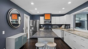 A modern kitchen with a central island, stainless steel appliances, and a large window. - Huge Backyard, Large Living Room with Dining Area, Large Den with Built-In... (Southampton)