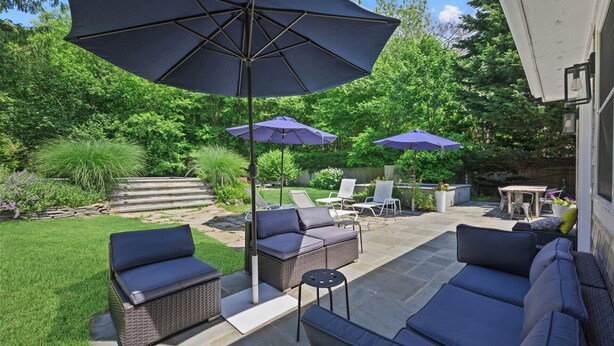 A patio with outdoor furniture, including sofas and chairs, under large umbrellas. - Huge Backyard, Large Living Room with Dining Area, Large Den with Built-In... (Southampton)