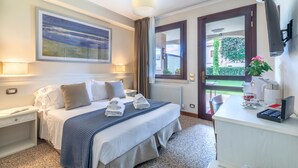 Una habitación de hotel con cama, mesitas de noche, cafetera y vistas al exterior.