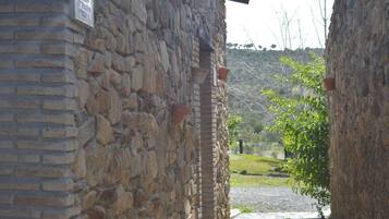 A stone building with a brick section, a pathway leading to a green area, and a sign on the wall.