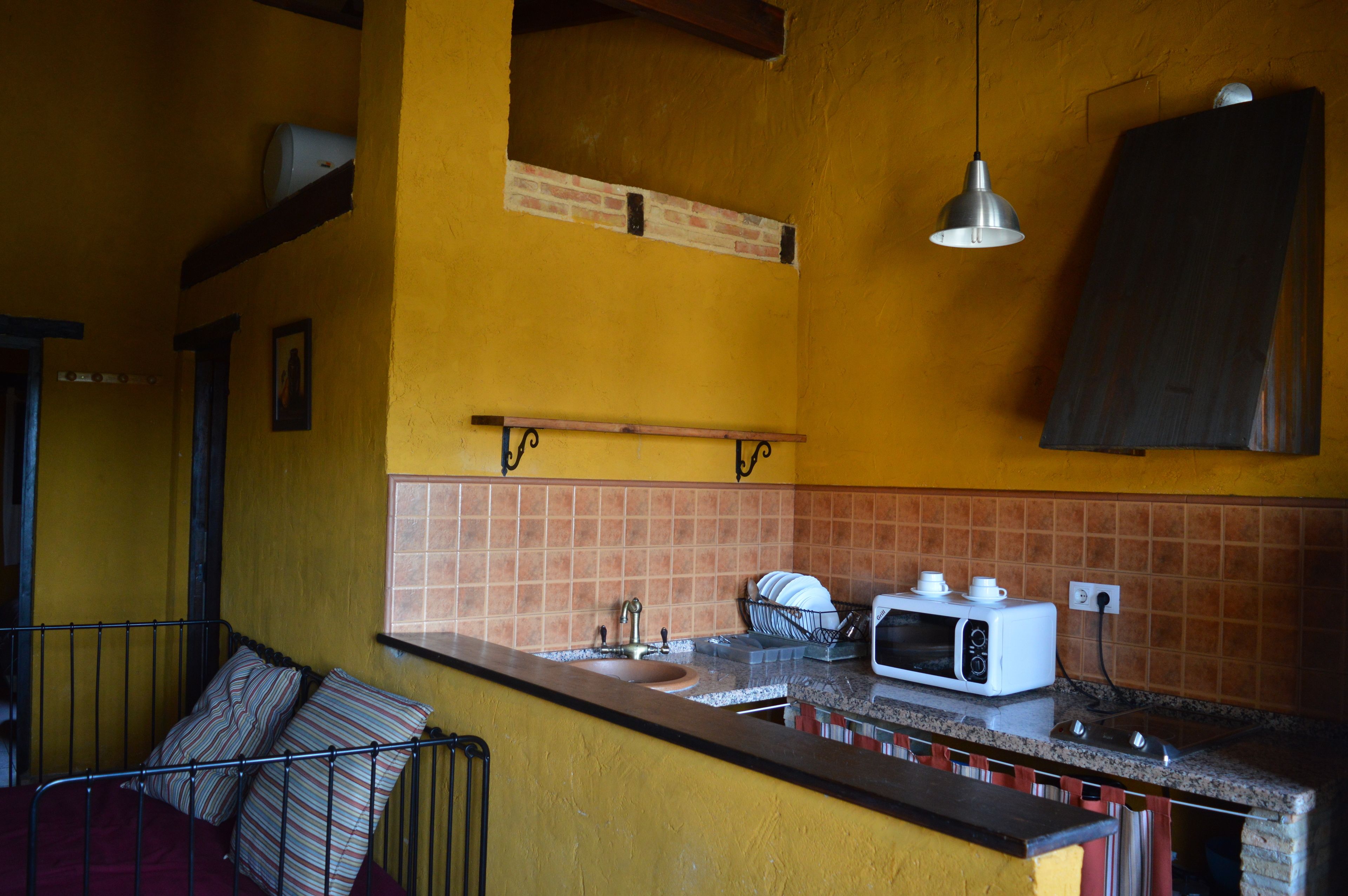 A compact kitchen with a sink, a microwave, and a hanging light fixture.